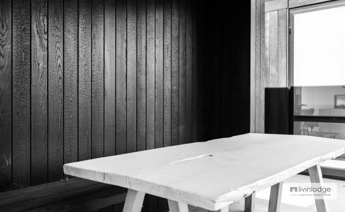 Witte houten tafel onder zwarte terrasoverkapping in gebrand hout Witte houten tafel onder zwarte terrasoverkapping in gebrand hout