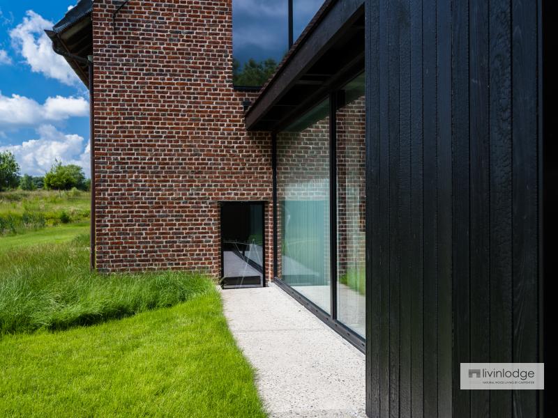 Moderne aanbouw in houtskelet met grote glaspartij en gebrand hout Moderne aanbouw in houtskelet met grote glaspartij en gebrand hout