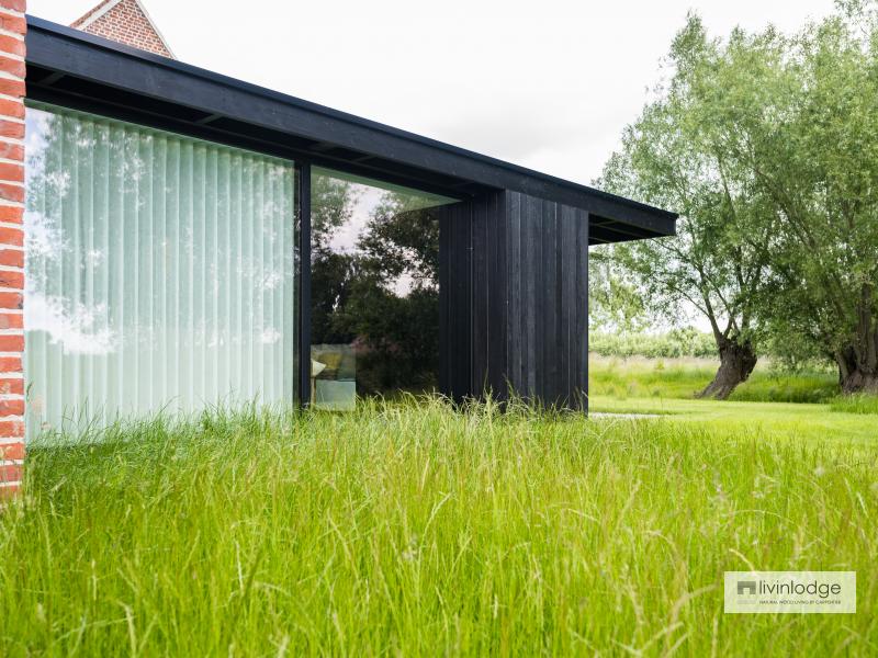 Moderne aanbouw aan oude hoevewoning opgetrokken in houtskelet Moderne aanbouw aan oude hoevewoning opgetrokken in houtskelet