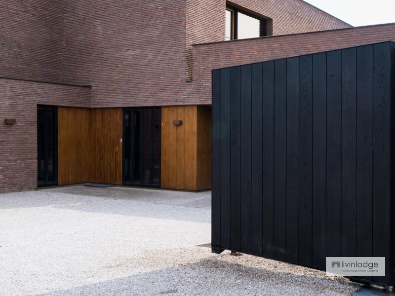 Portail en bois noir s'intégrant parfaitement à une villa moderne aux lignes épurées Portail en bois noir s'intégrant parfaitement à une villa moderne aux lignes épurées